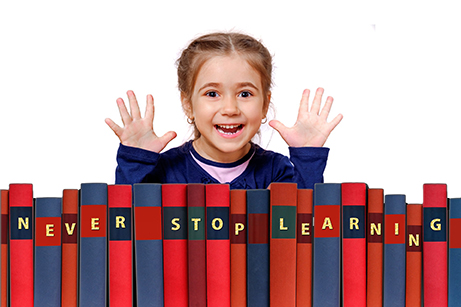 Barn tittar fram bakom böcker med texten never stop learning