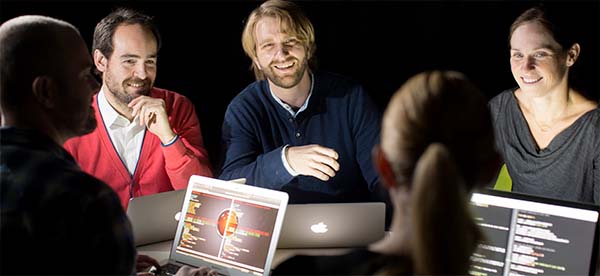 Forskare sitter runt ett bord med laptops och samtalar