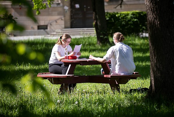 Två personer sitter vid ett bord i Engelska parken och pluggar