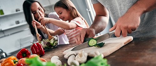 föräldrar hackar grönsaker med flicka