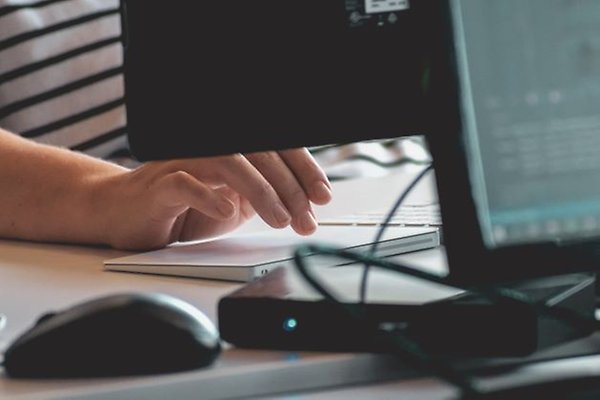 en person som skriver på ett tangentbord framför en datorskärm
