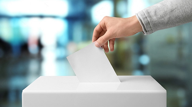 hand som lägger röstsedel i valurna.