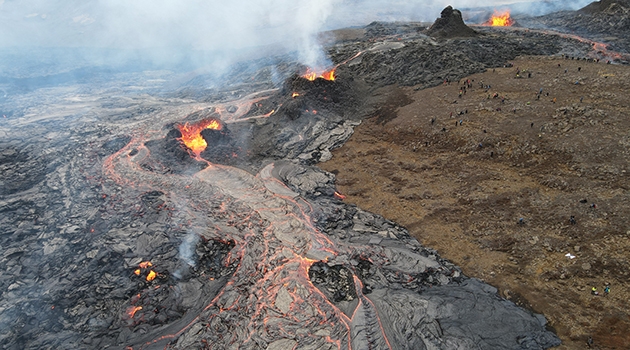 The Fagradalsfjall eruption site viewed from above. The photo shows lava emanating from multiple vents. Tourists for scale. 