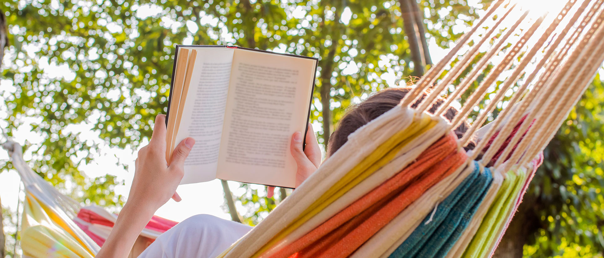 Person lying in a hammock reading.