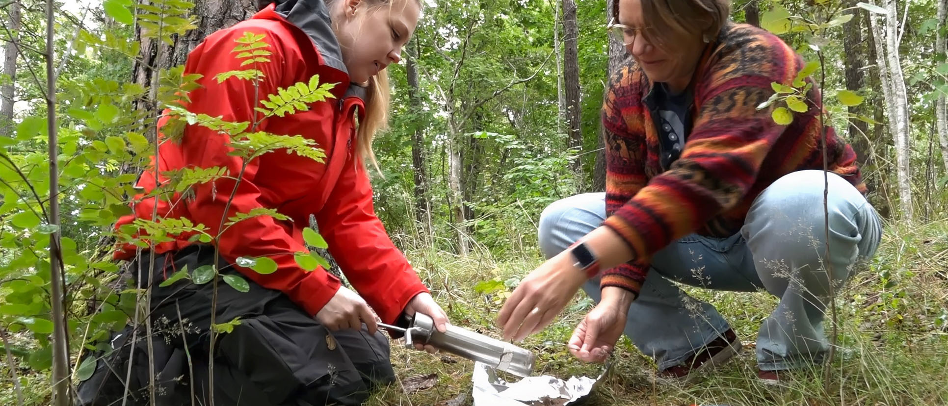 two researchers are squatting and taking samples from the earth