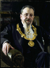 Porträtt av en man i kostym och mustasch, sittandes i en fåtölj