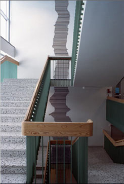 en stentrappa med grön ledstång och en grå smal väggmålning