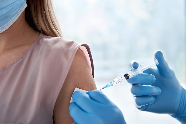 arm på kvinna i munskydd som vaccineras