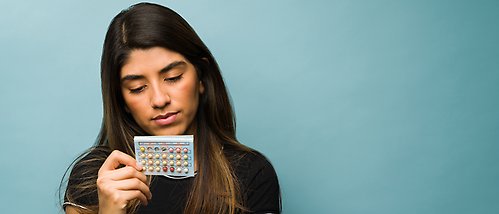 Kvinna som tittar ner på en p-pillerkarta i handen. 