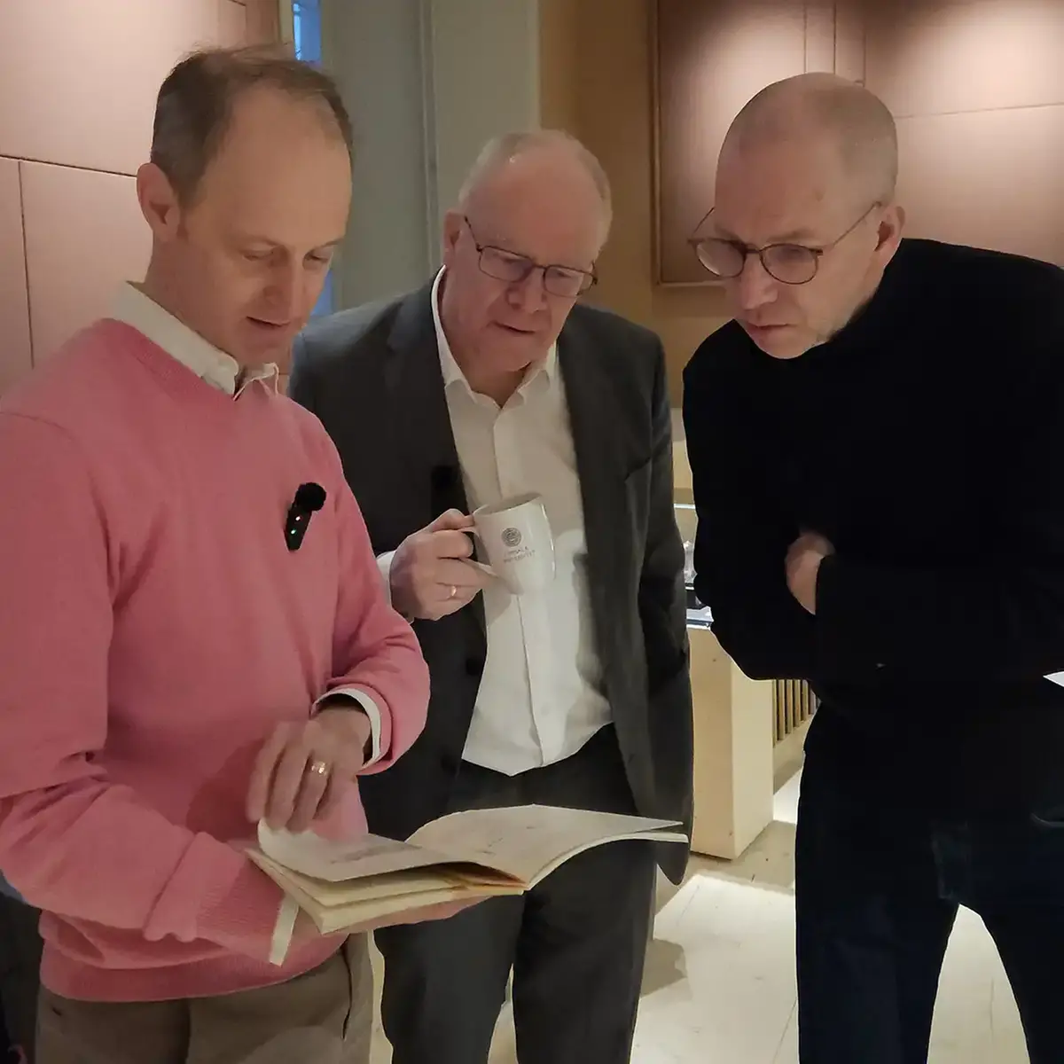 Tre män bläddrar i en bok.