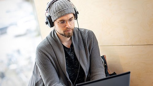 Student with headphones listening via a laptop.
