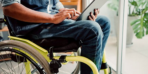 A person sitting in a wheelchair with a tablet in hand.