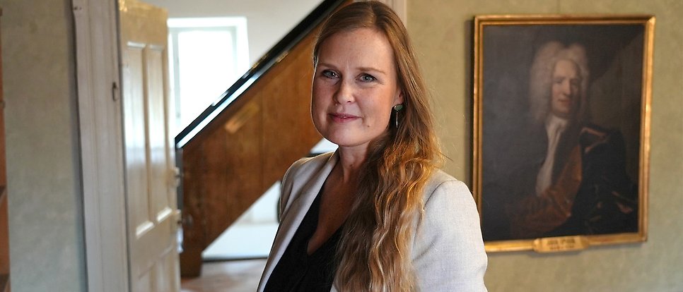 Portrait of gina gustavsson with a painting in the background.