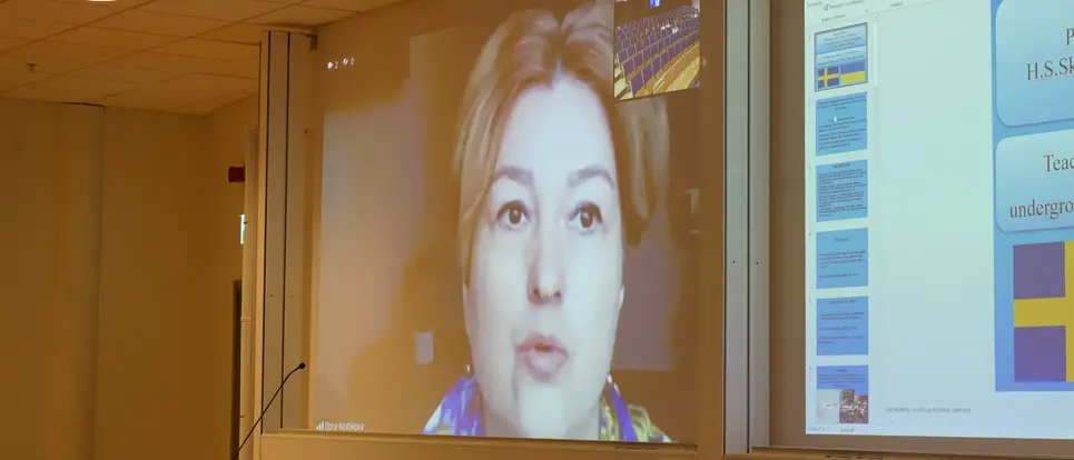 Lecturer Ilona Kostikova on a Zoom screen in a lecture theatre