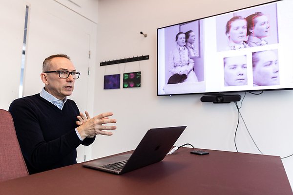 Anders Hast in front of a screen showing pictures of old portraits. 