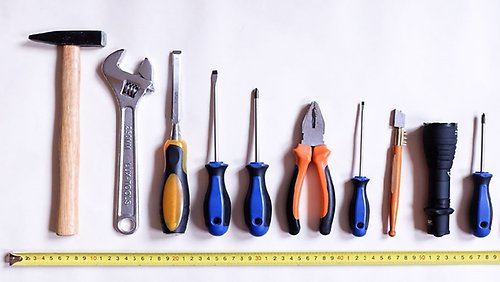 En rad med olika slags verktyg sorterade i storleksordning med ett utdraget måttband undertill.