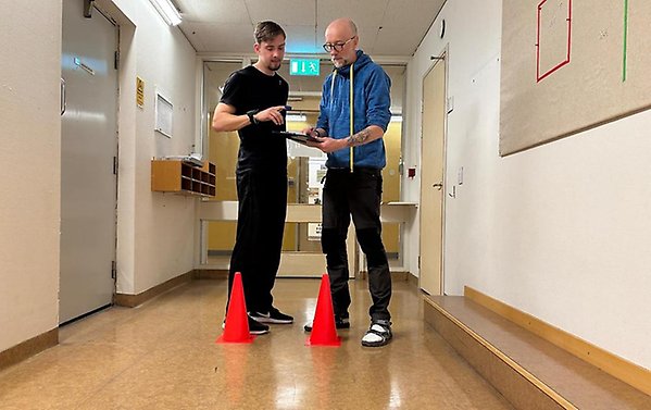 Två personer som står vid två koner och med tidtagarur