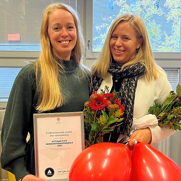 Porträttbild i labbmiljö av Anna Överby Wernstedt och Ylva Ivarsson med diplom och blommor