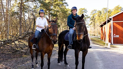 Coco Norén och Anders Hagfeldt rider på hästar utanför Akademistallet. 