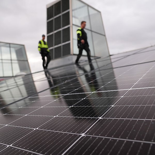 Två personer går på ett tak täckt av solceller.