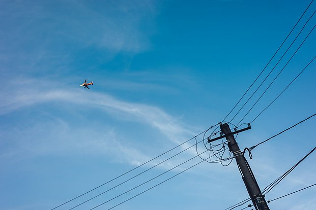 Flygplan som flyger i himlen över kraftledningar