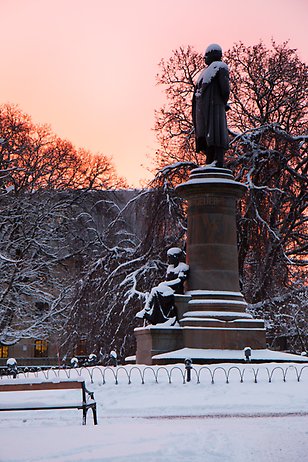Geijerstatyn i universitetsparken täckt av snö vid solnedgång