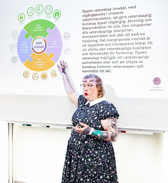 A person is pointing to a Powerpoint presentation. The presentation shows a slide in Swedish about open science.