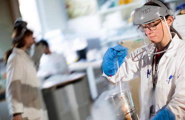 Kvinna i labbrock som arbetar i labb