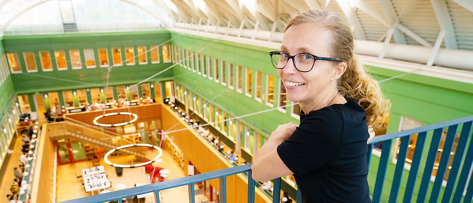 Inger Persson står på en balkong ovanför ekonomikums bibliotek. 