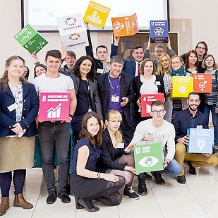 A group of people holding boxes covered in the UN:s Sustainable Development Goals