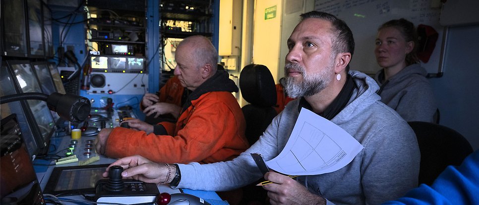 Several researchers are sitting in a dark control room.