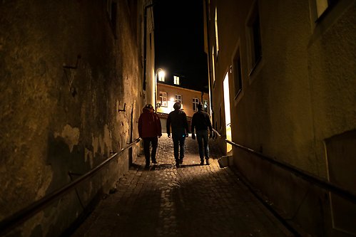Tre personer går i en gränd i Visby på kvällen.