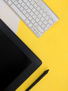 Digital penna och platta samt tangentbord mot gul bakgrund.
