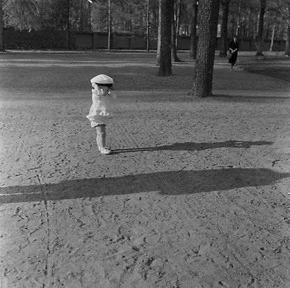 Liten pojke i gammaldags kläder på en grusgång