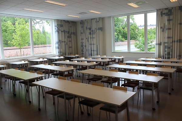 En typisk lärosal med rader av bord och stolar. / A typical classroom with rows of tables and chairs.