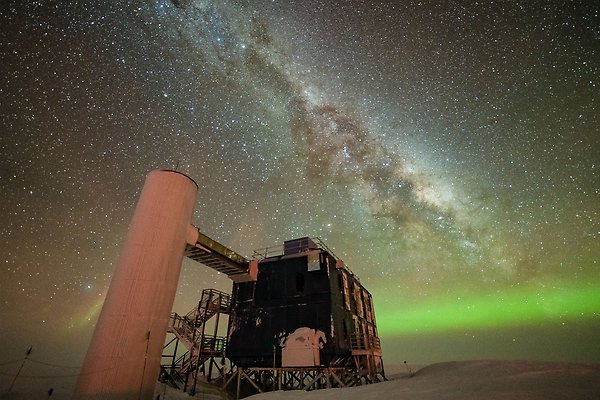 The IceCube telescope's research facility photographed so that you can see both the Milky Way and the northern lights in the background.