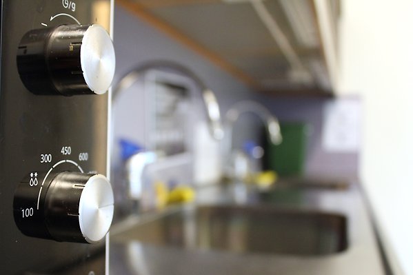 Närbild på en mikro och en vask i bakgrunden. / Close-up of a microwave with a sink in the background.