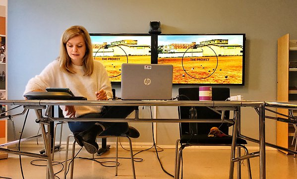 Emy Lindberg sitter med laptop framför en skärm.