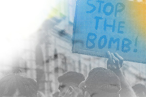 Bild på en demonstration där någon håller i ett plakat med texten Stop the bomb