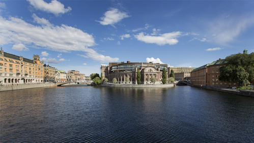 Västra riksdagshuset speglas i Strömmen. Till vänster i bild syns Rosenbad. Foto: Melker Dahlstrand/Sveriges riksdag.