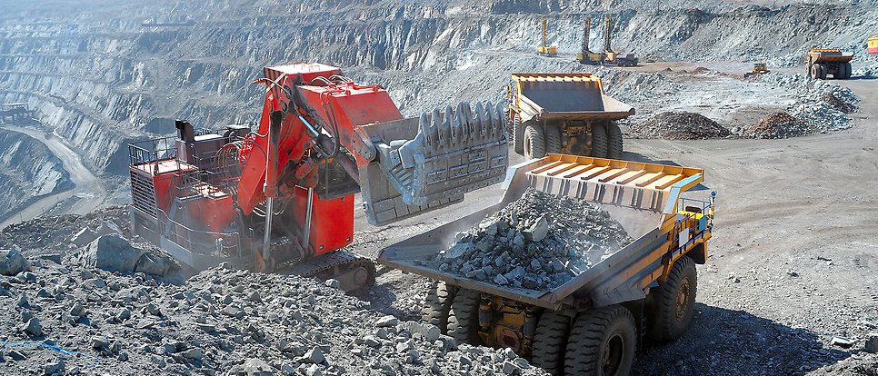 Dump trucks are loaded with iron ore in an open mine.