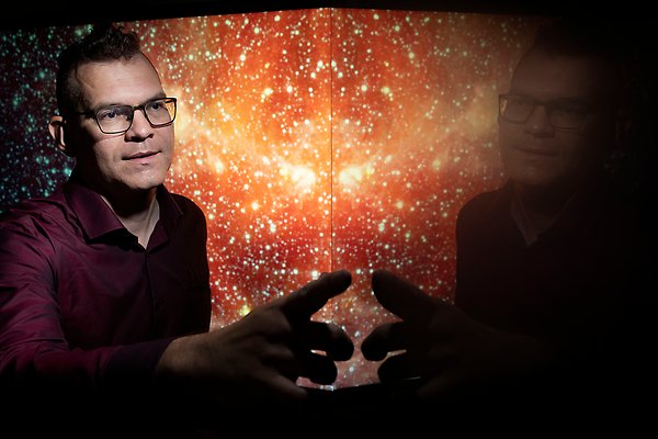 Erik Zackrisson framför en skärm som ser ut som en stjärnhimmel. 