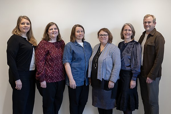 The six members of the management group lined up in front of white wall