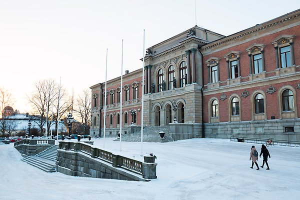 The front of the university main building on a snowy day with the castle in the background