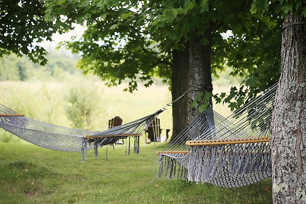 Bilden visar två hängmattor i en sommarvacker trädgård