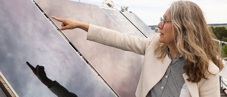 Marika Edoff pekar på en solpanel uppe på ett tak.
