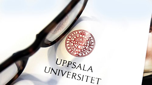 Glasögon på ett papper med Uppsala universitets logotyp