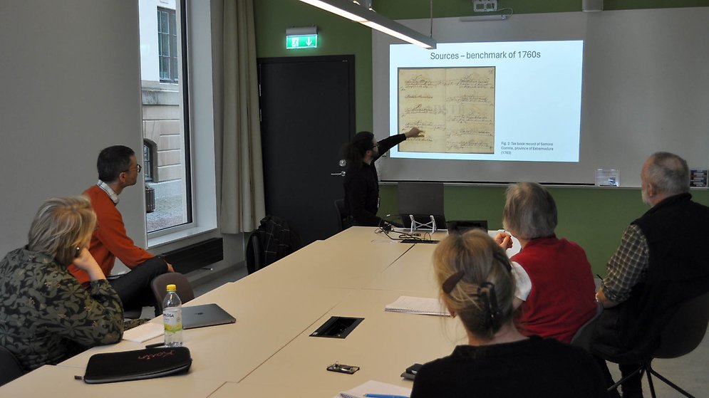 Ett seminarium pågår och en forskare pekar på en bild på en handskriven källa från 1700-talet medan de andra tittar interesserat.