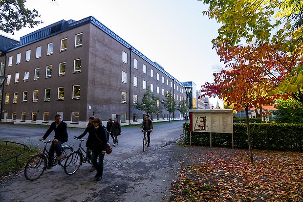 Fasad av Engelska parkens campus med höstträd och cyklande och gående studenter framför