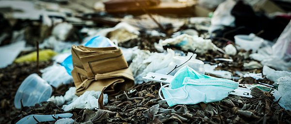 Engångsmunskydd och annat medicinskt avfall ligger dumpat bland förmultnande skräp på en soptipp.